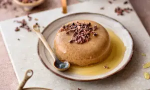 Schokoladenpudding mit Kakaonibs und Honig auf einem Teller mit Löffel.