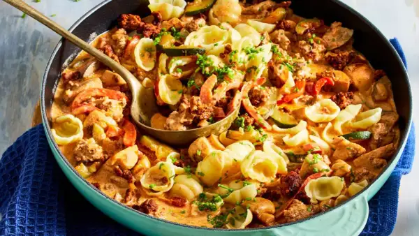 Hackfleisch-Nudel-Pfanne mit Zucchini und Paprika in cremiger Sauce, garniert mit Schnittlauch.
