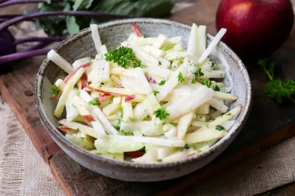Kohlrabisalat mit Apfelstücken und Petersilie in einer Schüssel.