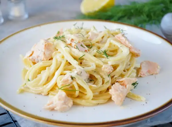 Spaghetti mit Lachs und Dill in cremiger Sauce auf einem Teller.